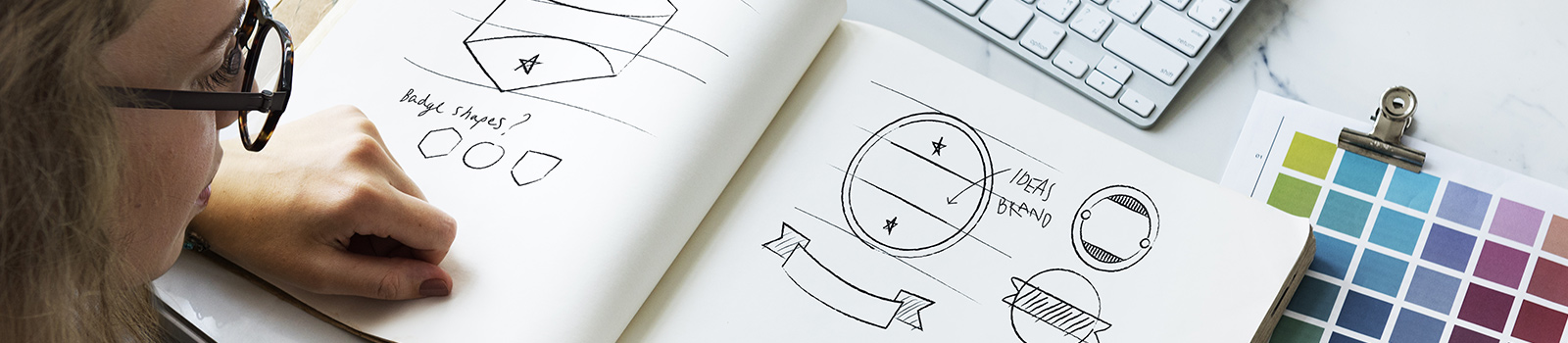 Designer looks at ideas for logo design and branding, using a sketch books and a color guide
